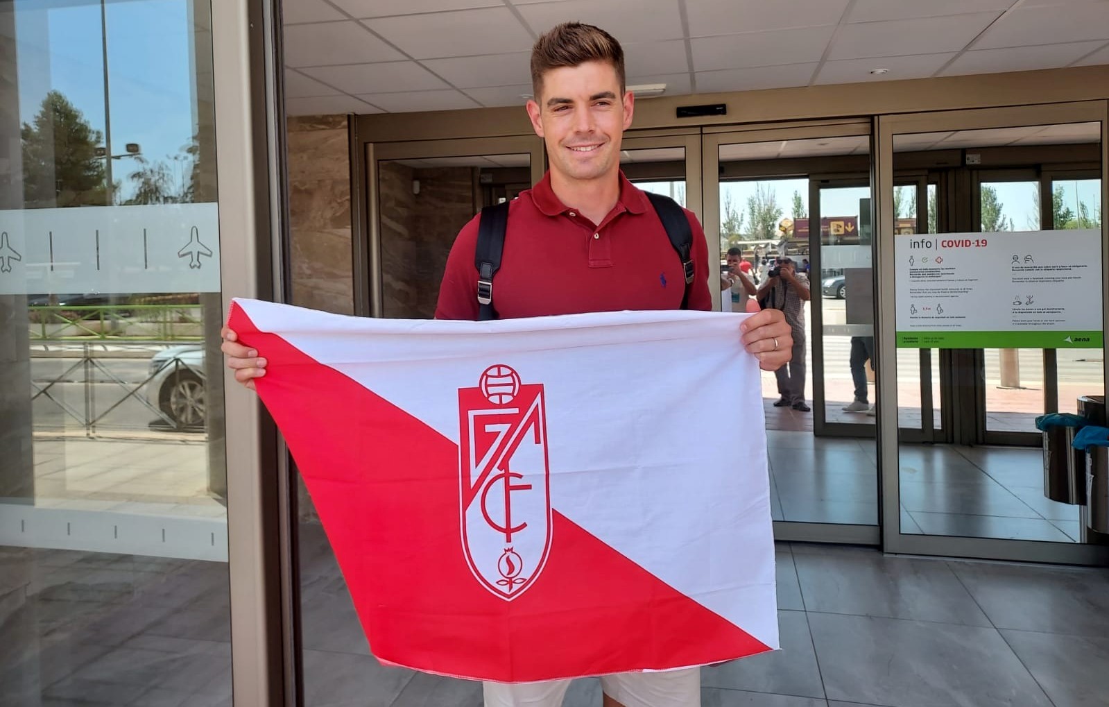 Raúl Fernández posa con una bandera del Granada a su llegada al aeropuerto (FRAN CALVO)